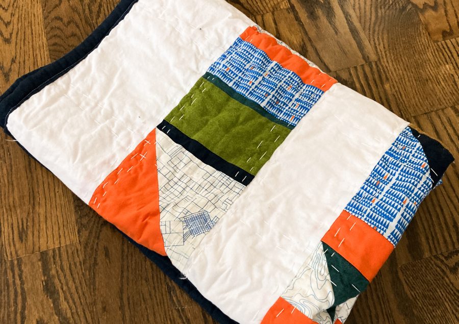 A folded quilt that features geometric blocks of color